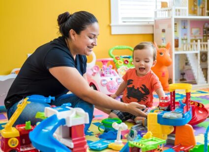 Professional nanny engaging a toddler in educational play activities at home.