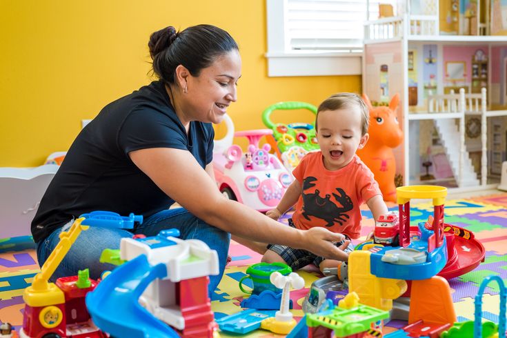 Professional nanny engaging a toddler in educational play activities at home.