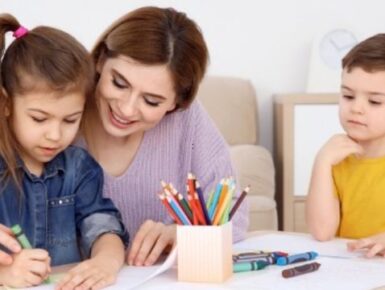 Professional nanny helping children with creative learning activities at home in Mumbai.