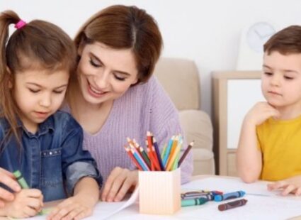 Professional nanny helping children with creative learning activities at home in Mumbai.