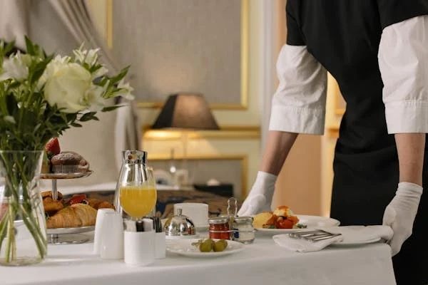 Professional household staff preparing and serving breakfast in a luxury home.